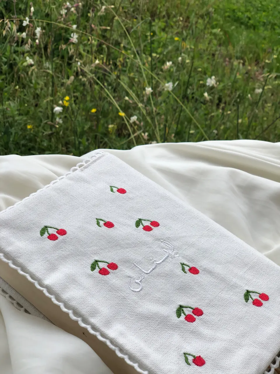 Protège-carnet en coton blanc semé de cerises brodées rouges, prénom arabe brodé blanc ton sur ton